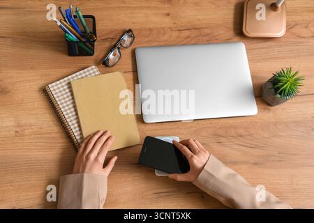 Weibliche Hände mit modernen Gadgets und Schreibwaren auf hölzernem Hintergrund Stockfoto