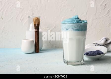 Glas blauer Dalgona Matcha Latte und Schüssel mit Pudermatcha auf Lichttisch Stockfoto