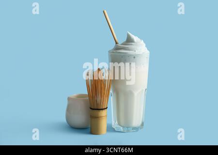 Glas blauer Dalgona Matcha Latte, Kanne und chasen auf blauem Hintergrund Stockfoto