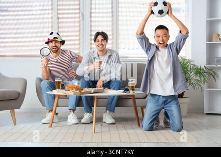 Männliche Freunde mit Bier, die zuhause Fußball gucken Stockfoto