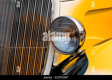 Nahaufnahme der glänzenden Stirnleuchte eines orangen Oldtimers. Stockfoto