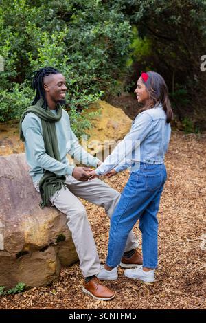 Verschiedene Paare halten Hände und lächeln auf verwitterter Felsenbank mit Holzspäne Stockfoto