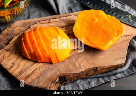 Geschnittene Mango auf einem Schneidebrett aus Olivenholz: Nahaufnahme einer geschälten, entkernten und geschnittenen Mango Stockfoto