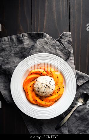 Mango Sticky Rice mit Kokosnusssauce in einer flachen Schüssel Overhead: Thailändisches Dessert mit klebrigem Reis, frischem Obst und gerösteten Sesamsamen Stockfoto