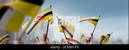 Brunei-Fahnen in den Händen auf einem verschwommenen urbanen Hintergrund Stockfoto