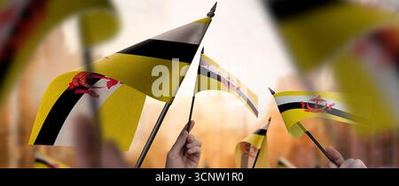 Brunei-Fahnen in den Händen auf einem verschwommenen urbanen Hintergrund Stockfoto
