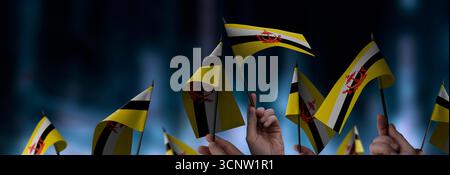 Brunei-Fahnen in den Händen auf einem verschwommenen urbanen Hintergrund Stockfoto