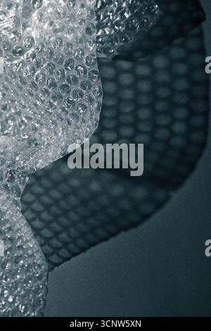Nahaufnahme der Luftpolsterfolie, die geometrische Schatten auf einer Oberfläche erzeugt. Abstrakte Minimaltextur bei monochromem Licht. Stockfoto