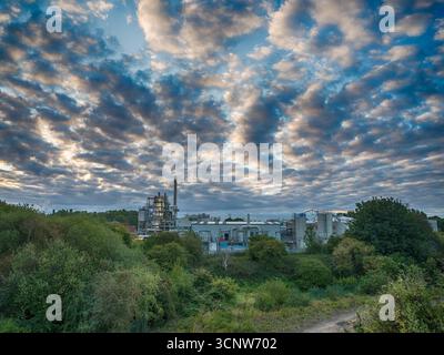 Industrieanlagen und Fabrikgebäude mit dramatischer Wolkenlandschaft darüber Stockfoto