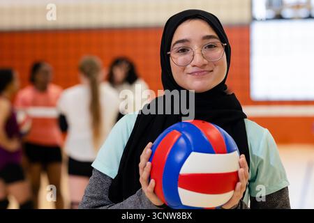 Verschiedene weibliche Mannschaftskameraden in Sportbekleidung halten Volleybälle, reden über das Fitnessnetz, Kopierraum Stockfoto