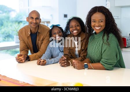 Vielfältige Familie, die sich auf der weißen Kücheninsel in der Nähe von rotem Toaster und Smartwatch befindet Stockfoto