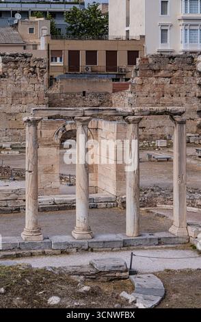 Die antike römische Agora in Athen verfügt über markante Marmorsäulen, die sich an historischen Steinmauern befinden und die Antike mit moderner städtischer Architektur verbinden Stockfoto