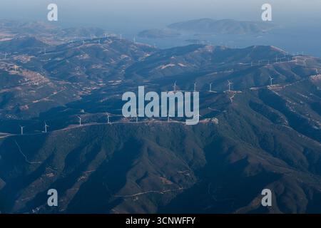 Panoramablick auf Griechenlands malerische Berglandschaft, gespickt mit Windturbinen und umgeben vom azurblauen Meer und den fernen Inseln, A Stockfoto