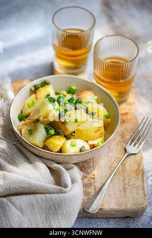 Ein köstlicher griechischer Kartoffelsalat, serviert in einer Keramikschale, garniert mit frischen Kräutern und Kapern. Ideal für eine leichte Mahlzeit oder Beilage, perfekt für Medit Stockfoto