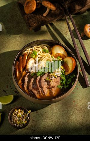 Blick von oben auf die köstliche Schüssel Entenramen mit zarten Scheiben Ente, Einudeln und Shiitake-Pilzen. Garniert mit frischer Minze, Sprossen und Stockfoto