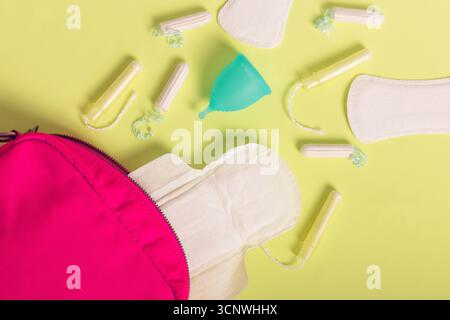 Draufsicht auf verschiedene Hygieneprodukte für Frauen, einschließlich Menstruationsbecher, Tampons und Hygienepads. Vor einem hellen Hintergrund befördern sie mich Stockfoto