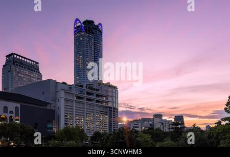Atemberaubender Blick auf Bangkoks Geschäfts- und Finanzviertel in Thailand mit modernen Wolkenkratzern unter einem lebendigen, farbenfrohen Abendhimmel. Stockfoto