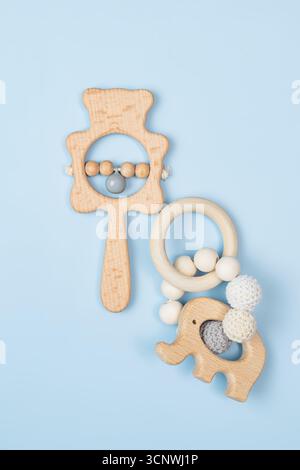 Eine bezaubernde Ausstellung von hölzernen Babyspielzeugen auf einem sanften blauen Hintergrund. Zu den umweltfreundlichen Spielzeugen gehören eine bärenförmige Rassel und ein Elefantenbeißring, perfekt Stockfoto