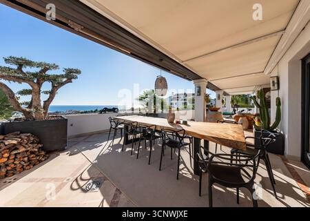 Luxuriöse Außenterrasse mit Meerblick und Holztisch im mediterranen Penthouse Stockfoto