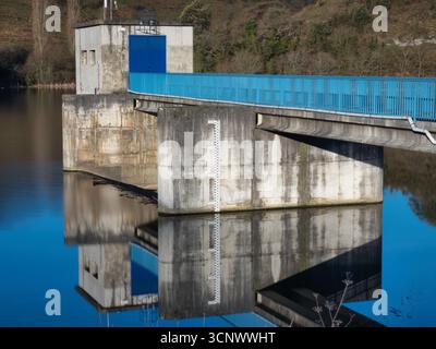 Abstrakte Staumauer mit Wasserstand - eine abstrakte, weite Aufnahme einer Staumauer mit einem hellblauen Gang und einer Wasserstandsanzeige, die alle auf dem Kalk reflektiert werden Stockfoto