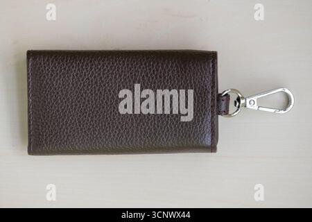 Stilvoller Schlüsselhalter aus Leder auf hellbraunem Hintergrund. Stockfoto