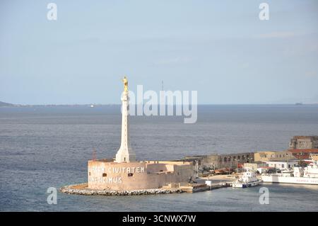 Eine Statue unserer Dame des Briefes am Eingang des Hafens von Messina. Meer im Hintergrund an einem sonnigen Tag Stockfoto