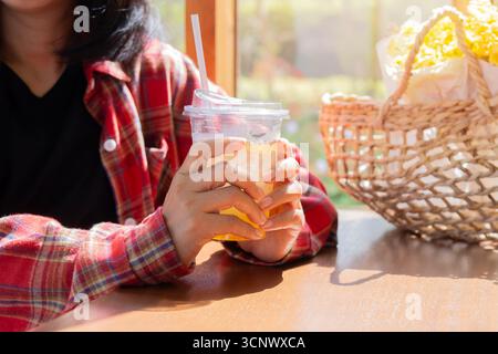Nahaufnahme Frau, die in einem Café Tassen Eistee auf dem Tisch hält. Selektiver Fokus. Stockfoto