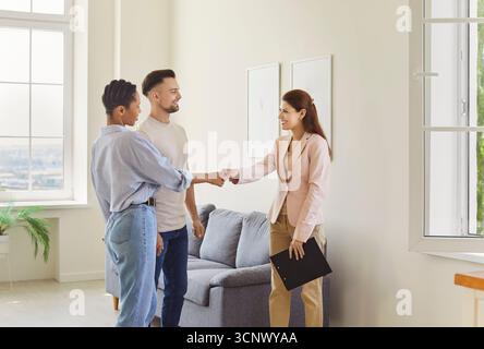 Immobilienmakler, Immobilienmaklerin trifft Klientenpaar, um zu handeln, zu zeigen, neue Immobilien zu präsentieren, zu zittern Stockfoto