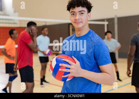 Verschiedene männliche Teams in Trikots im Netz auf dem Platz, die rote, weiße und blaue Volleyballübungen halten Stockfoto