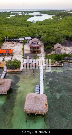 Aus der Vogelperspektive eines tropischen Resorts auf dem Archipel der San Bernardo-Inseln, Kolumbien. Mit üppigem Grün, Holzsteg, Strohdächern und Vibr Stockfoto