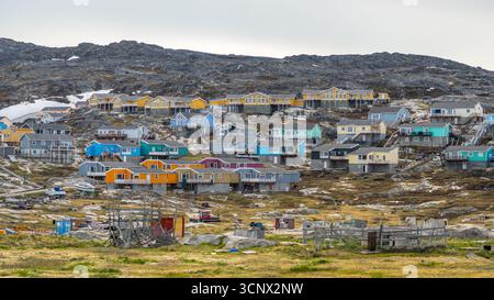 Lebendige Häuser in Ilulissat, Grönland, eingebettet auf felsigen Hügeln mit einer einzigartigen Mischung von Farben. Diese malerische Aussicht fängt den Charme des arktischen Dorfes und ein Stockfoto