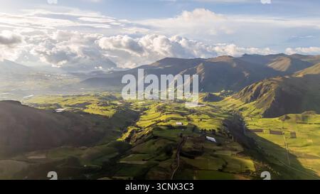 Ein atemberaubender Blick aus der Luft auf die üppige, grüne Landschaft in Cayambe, Ecuador. Die sanften Hügel und Täler werden von der sanften Sonne wunderschön hervorgehoben Stockfoto