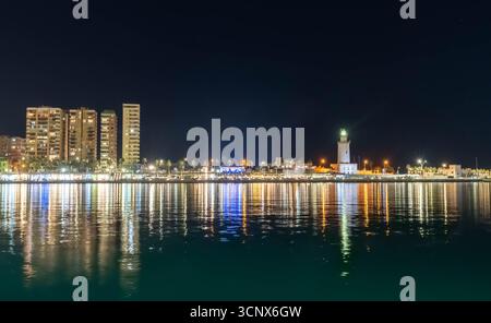 Blick vom Hafen von Malaga bei Nacht mit Wasserspiegelung Stockfoto
