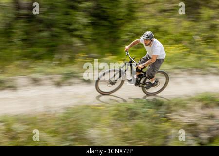Ein Mann fährt mit dem Mountainbike über einen malerischen Waldweg in Zermatt und bietet ein aufregendes Outdoor-Abenteuer. Die dynamische Bewegung erfasst das Th Stockfoto