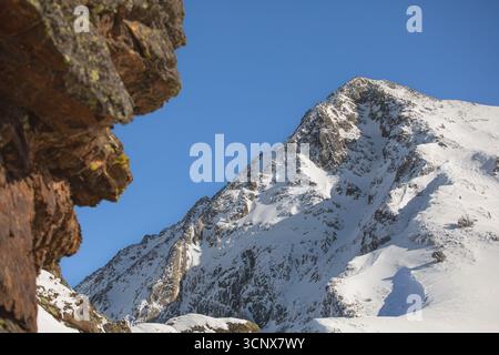 Der majestätische, schneebedeckte Berggipfel in den Pyrenäen erhebt sich scharf gegen einen tiefblauen Himmel. Schroffe Klippen und unberührter Schnee vermitteln Abenteuer und alpine wilde Stockfoto