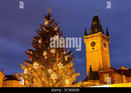 Der beleuchtete Weihnachtsbaum mit Ornamenten und Lichtern steht in der Nähe des Turms des Prager Alten Rathauses Stockfoto