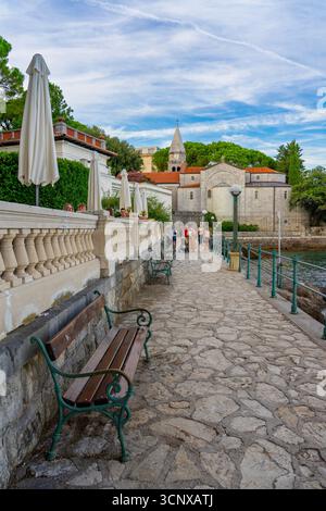 Wunderschöne Küstenpromenade in Opatija, Kroatien, mit einem Steinweg entlang der Adria, wo sich die Leute in einem Café am Meer entspannen. Die Szene in Stockfoto