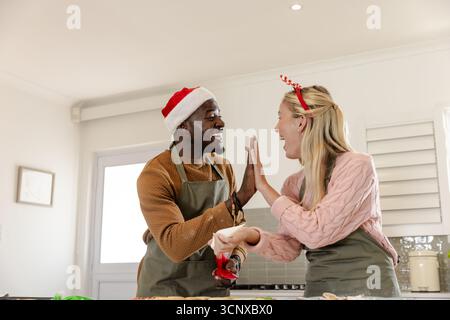 afroamerikanisches Paar High-Five beim Rollen von Keksteig in moderner Küche mit Nudelnadel Stockfoto