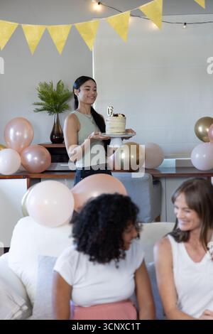 Verschiedene Freundinnen feiern Geburtstag, mit goldenem 30 Kuchen im dekorierten Wohnzimmer Stockfoto