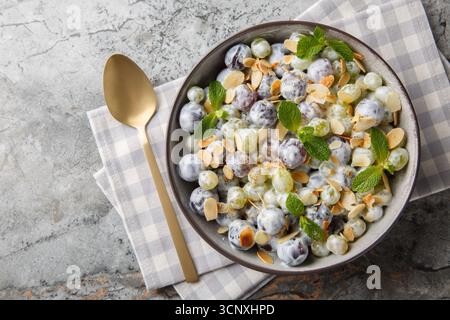 Frischer süßer Sultana-Traubensalat mit Mandelflocken, Minze, griechischem Joghurt und Frischkäse-Dressing in Nahaufnahme auf einem Teller auf dem Tisch. Horizontale Draufsicht Stockfoto
