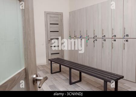 Holzbank und Schließfächer im Umkleideraum Stockfoto