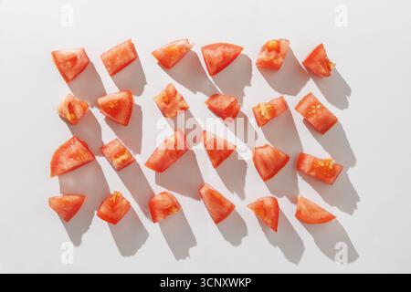 Reihen roter Tomatenstücke auf weißem Hintergrund. Draufsicht Stockfoto