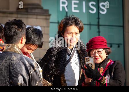 Eine Gruppe asiatischer Menschen in traditioneller Kleidung, die ein Selfie an einem sonnigen Tag in newcastle chinese New Year CNY machen Stockfoto
