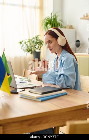 Eine rothaarige Lehrerin führt Onlinekurse von ihrem gemütlichen Heimbüro aus. Stockfoto