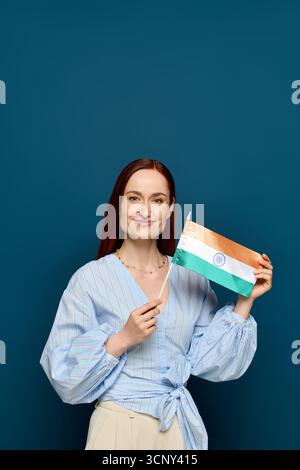 Ein dynamischer Sprachlehrer mit auffälligen roten Haaren hält eine Flagge und feiert die Kultur. Stockfoto