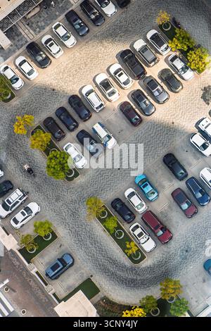 Aus der Vogelperspektive eines Parkplatzes mit verschiedenen Autos, die ein organisiertes Muster zwischen den Fahrzeugen und die umliegende Stadtlandschaft Dubai VAE zeigen Stockfoto