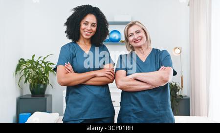 Zwei weibliche Physiotherapeuten stehen in Einer klinischen Therapie selbstbewusst mit gekreuzten Armen Stockfoto