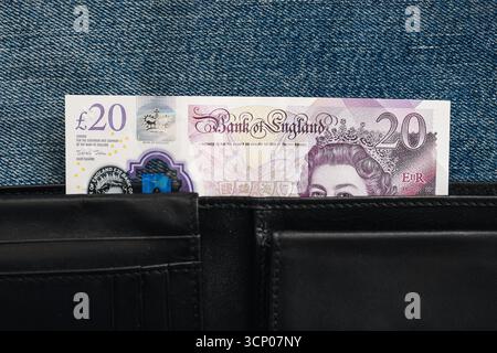 Britische 20-Pfund-Banknote in schwarzer Ledertasche. Nahaufnahme des Geldes in der Tasche. Finanz- und Sparkonzept. Details der Währungsnotiz. Stockfoto