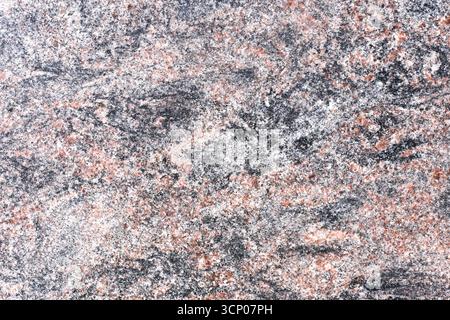 Graue und rosafarbene Granitsteinoberfläche. Natürliche mineralische Hintergrundstruktur. Grobe felsige Detailansicht. Harte geologische Struktur. Abstraktes Festmaterial. Stockfoto