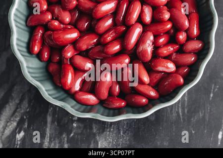 Frische rote Kidneybohnen in grüner Schüssel. Organische Leguminosen-Nahaufnahme. Gesunde vegetarische Eiweißkost. Natürlicher Nährstoffbestandteil. Rohe Bohnen zum Kochen. Stockfoto